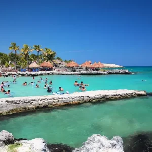 Playa paradisíaca de Playa del Carmen con aguas turquesas del Caribe Mexicano y visitantes disfrutando de la costa durante un viaje de 7 días.